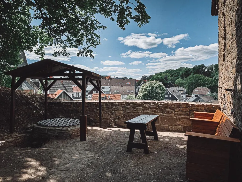 Burghof mit Holzpavillon, Brunnen und Sitzbänken an der Burgmauer
