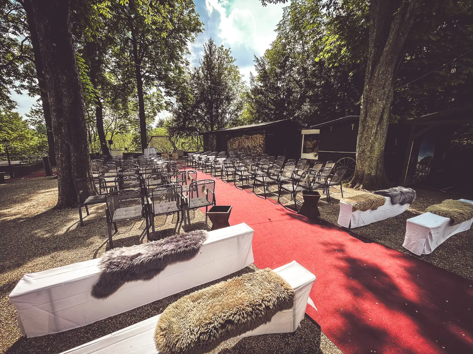 Freie Trauung im Burggarten mit rotem Teppich und Stuhlreihen unter alten Bäumen